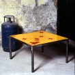 Tavolo basso 80X80 cm. Struttura in ferro grezzo e piano in resina colorata con inserti.